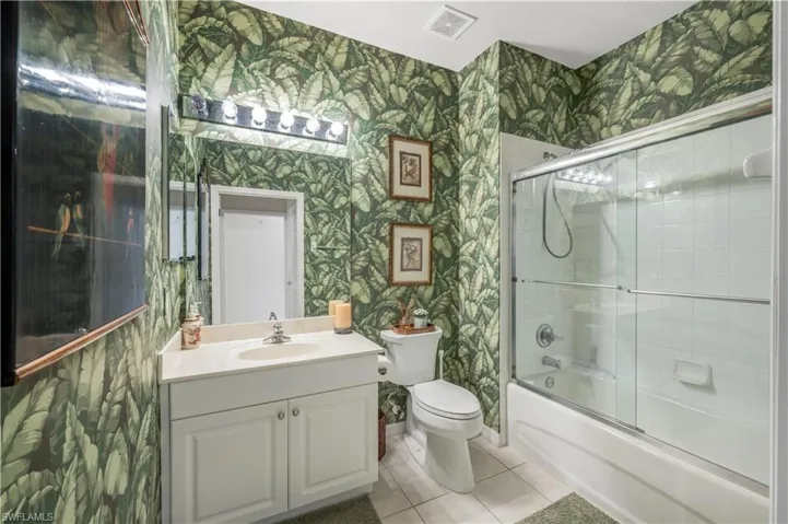 Full bathroom with visible vents, vanity, and wallpapered walls