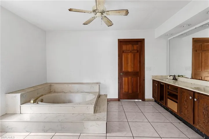 Bathroom featuring vanity, a tub to relax in, and tile patterned flooring