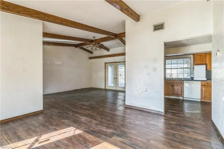 Unfurnished living room with french doors, lofted ceiling with beams, dark hardwood / wood-style floors, and ceiling fan