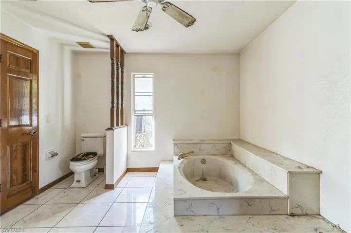 Bathroom with a bathtub, toilet, tile patterned flooring, and ceiling fan