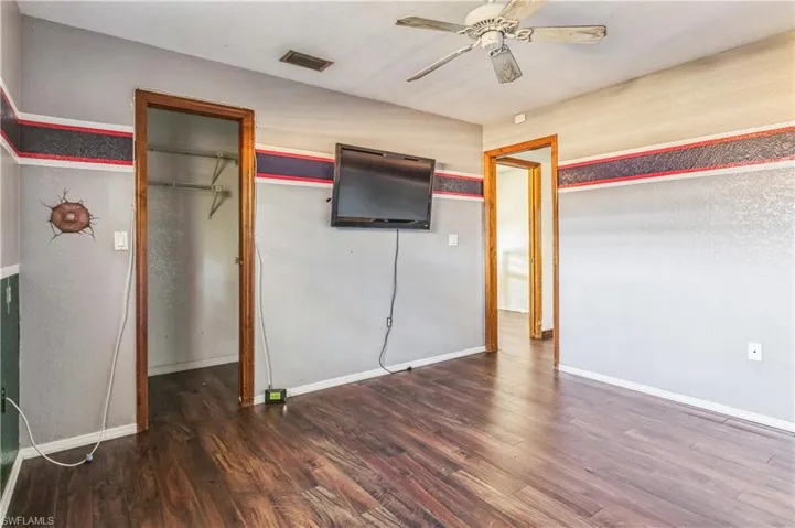 Unfurnished bedroom featuring dark hardwood / wood-style floors, a closet, and ceiling fan