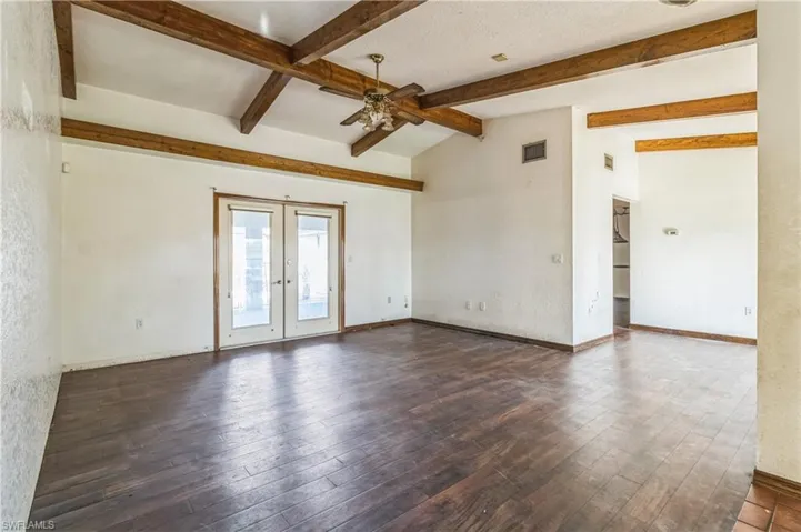 Spare room featuring french doors, ceiling fan, vaulted ceiling with beams, and dark hardwood / wood-style flooring