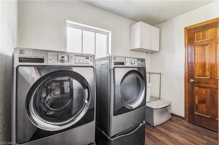 Laundry area with dark wood-type flooring, separate washer and dryer, and cabinets