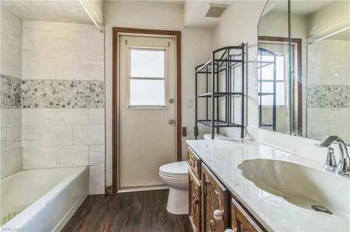 Bathroom featuring toilet, vanity, wood-type flooring, and plenty of natural light