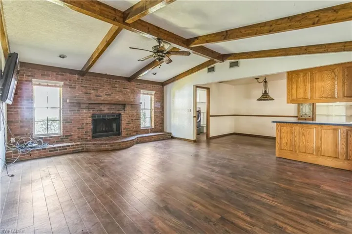 Unfurnished living room with lofted ceiling with beams, a textured ceiling, a fireplace, and dark hardwood / wood-style floors