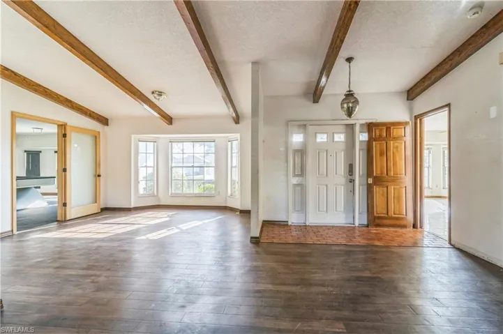Foyer entrance featuring beam ceiling, a textured ceiling, and dark hardwood / wood-style floors