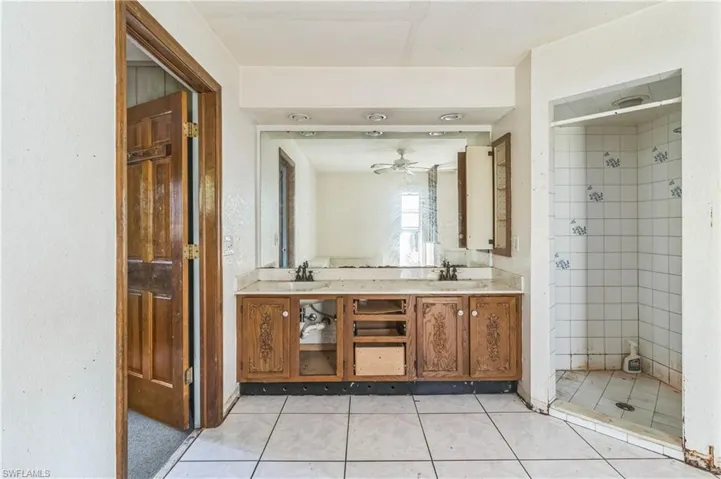 Bathroom with vanity, ceiling fan, and tiled shower