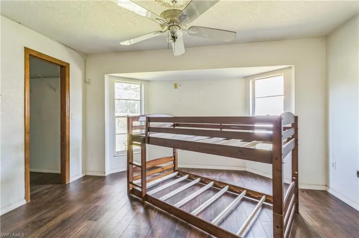 Bedroom featuring dark wood-type flooring, ceiling fan, a closet, and a textured ceiling