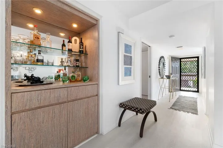 Indoor dry bar with open shelves, light brown cabinetry, light wood-style flooring, and light countertops