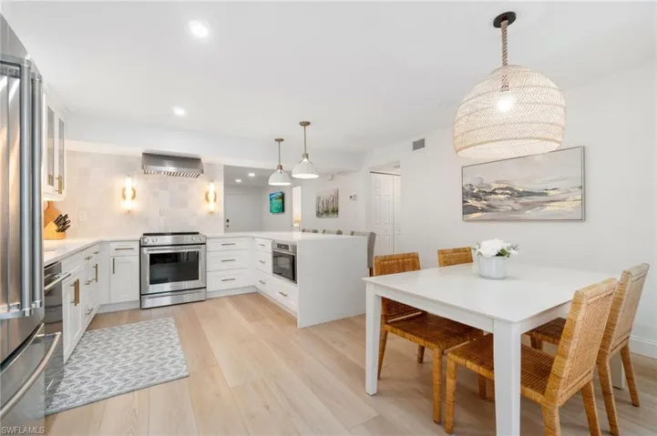 Kitchen featuring pendant lighting, a peninsula, white cabinets, and light stone counters