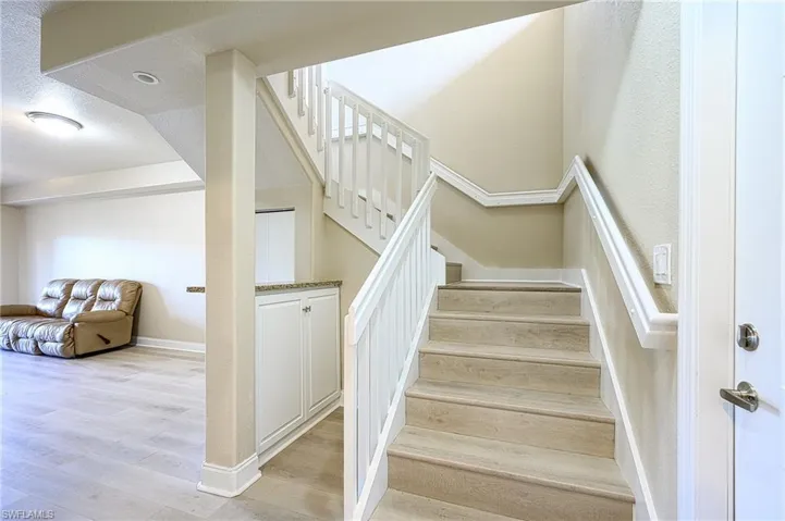 Staircase with a textured ceiling and light hardwood / wood-style floors