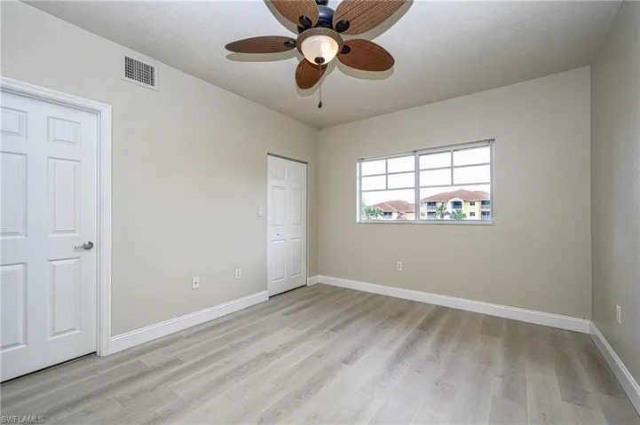 Main ensuite bedroom with light hardwood / wood-style flooring and ceiling fan - large walk in closet