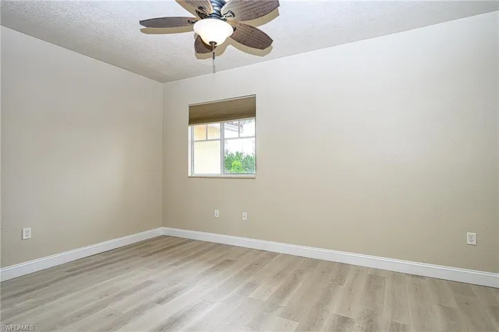 Guest bedroom / ensuite with light hardwood / wood-style flooring, a textured ceiling, and ceiling fan