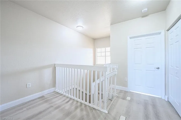 Den area in loft with a textured ceiling and hardwood / wood-style floors