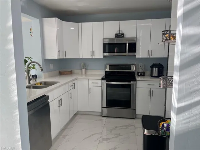 Kitchen featuring white cabinets, sink, and stainless steel appliances