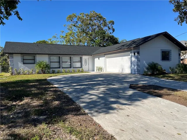 Ranch-style house with stucco siding, an attached garage, driveway, a front lawn, and a shingled roof