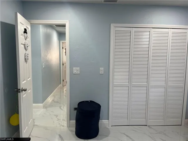 Hallway featuring baseboards, marble finish floor, and visible vents