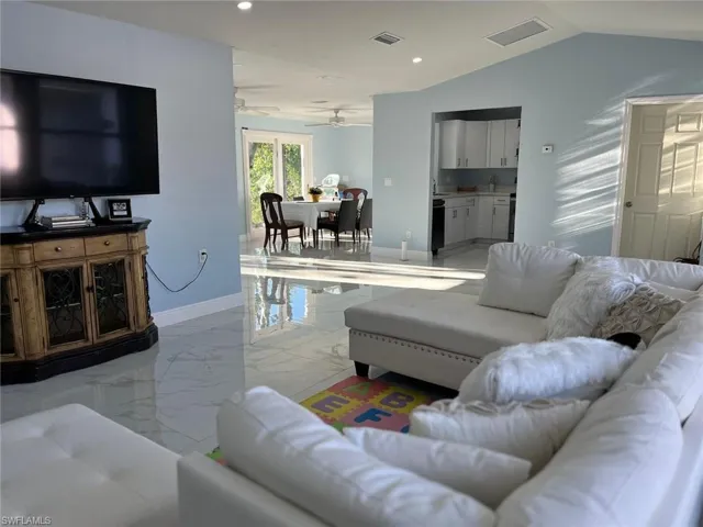 Living room featuring ceiling fan and vaulted ceiling