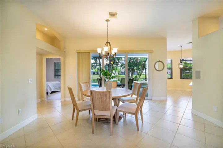 Dining area with a ceiling fan, suspended lighting, arched walkways, and light tile patterned flooring