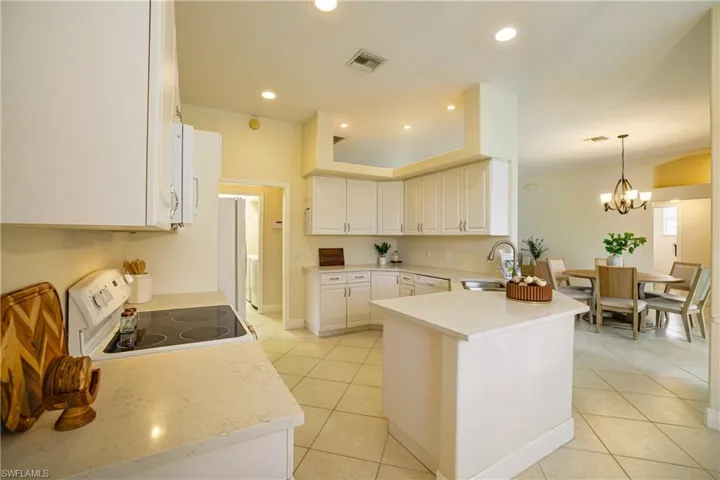 Kitchen featuring white appliances, a peninsula, plenty of natural light, and light tile patterned floors