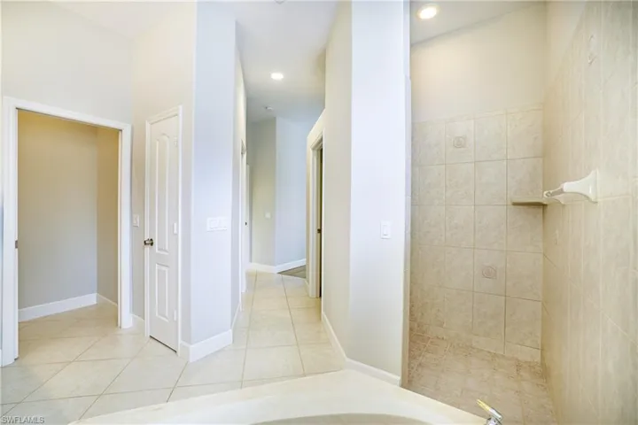 Bathroom with double vanity, a bath, and light tile patterned floors