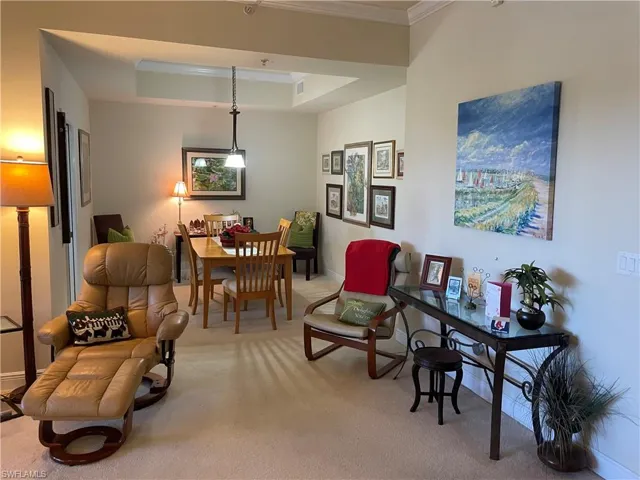 Living room with a tray ceiling, light colored carpet, and ornamental molding