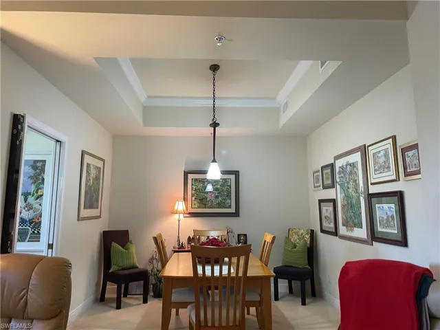 Dining room featuring ornamental molding, light carpet, and a tray ceiling