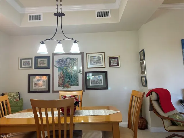 Dining area with ornamental molding, a tray ceiling, and an inviting chandelier