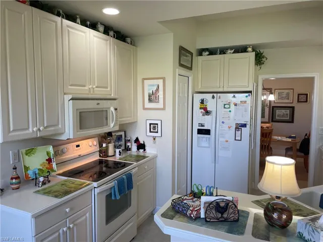 Kitchen with white cabinets, white appliances, and tile patterned floors