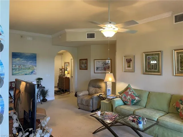 Living room with ceiling fan, carpet, and ornamental molding