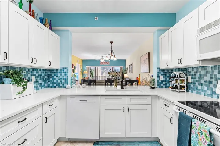 Kitchen with white appliances, white cabinets, tasteful backsplash, and light stone countertops