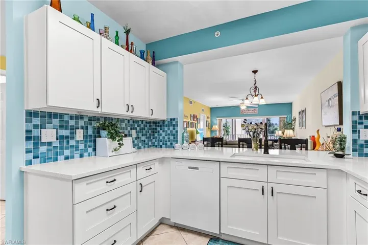 Kitchen featuring tasteful backsplash, dishwasher, light stone counters, and white cabinetry