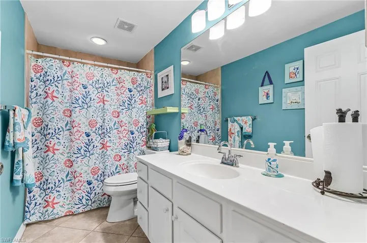 Bathroom with vanity, curtained shower, and light tile patterned flooring