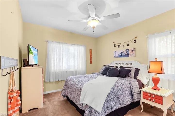 Carpeted bedroom with multiple windows and a ceiling fan