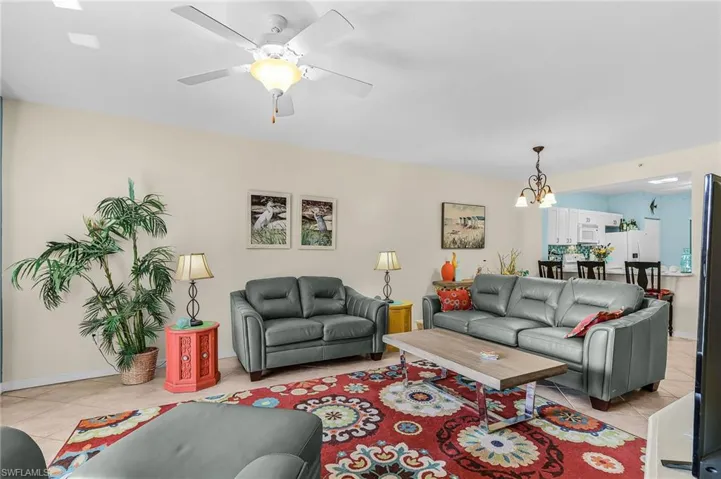Living room with light tile patterned floors, a ceiling fan, and a chandelier