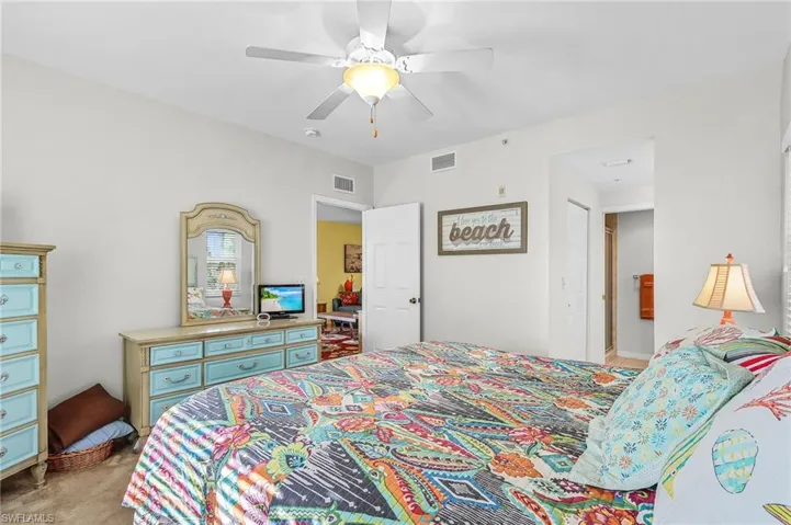 Bedroom with a ceiling fan, light colored carpet, and connected bathroom