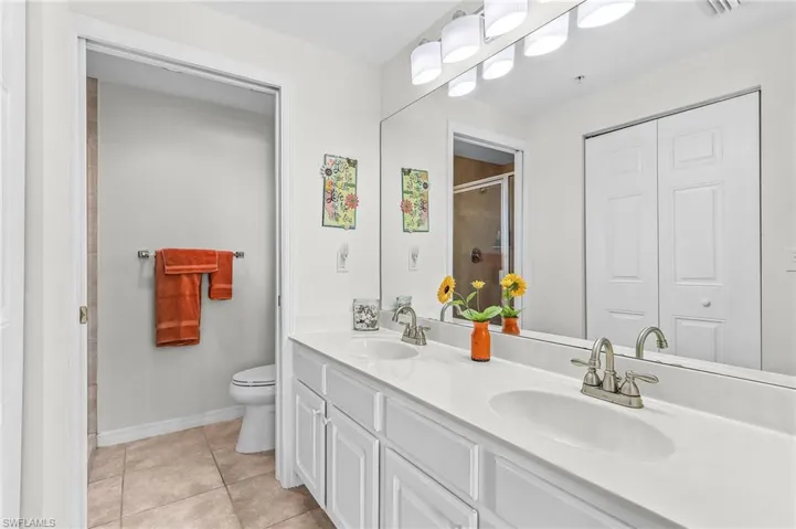 Bathroom with double vanity, light tile patterned floors, a closet, and a stall shower
