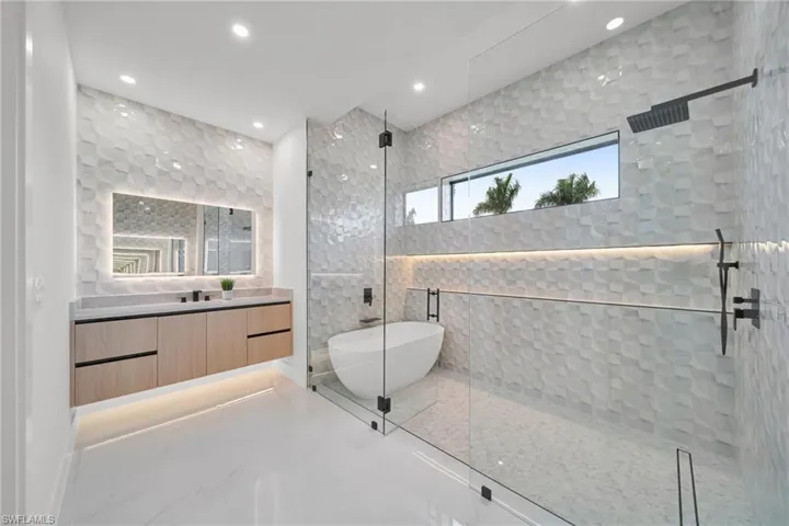 Full bath with a walk in shower, vanity, a freestanding tub, recessed lighting, and marble finish flooring