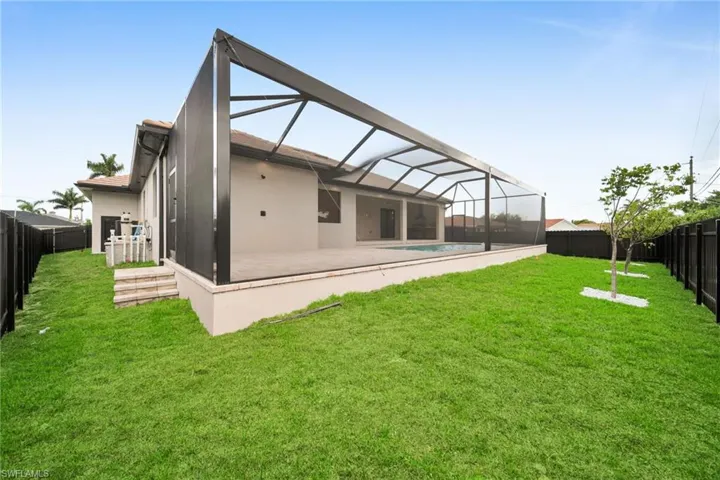 Rear view of house with a fenced backyard, a patio, stucco siding, and glass enclosure