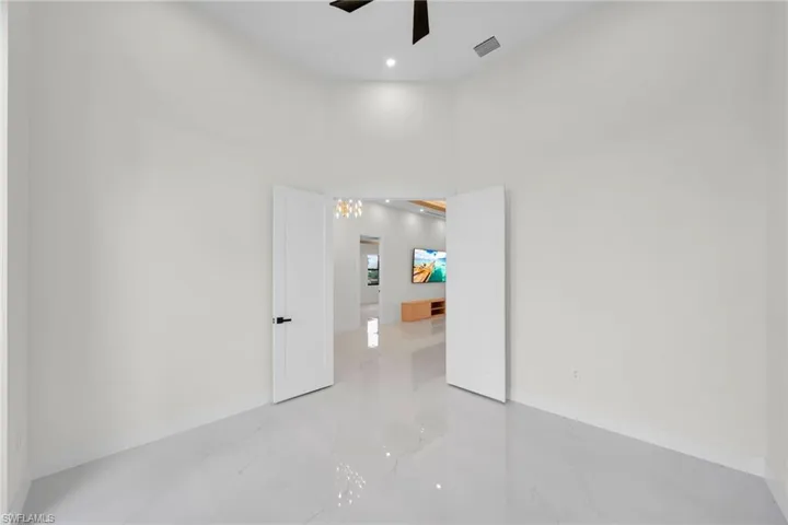 Unfurnished room with light marble finish floors, ceiling fan, a towering ceiling, and recessed lighting