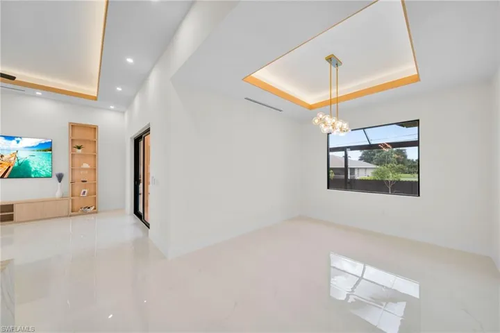 Unfurnished room featuring a raised ceiling, a chandelier, recessed lighting, and marble finish flooring