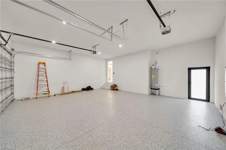 Garage featuring a garage door opener and electric water heater