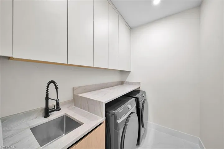 Laundry room with independent washer and dryer, cabinet space, and marble look tile flooring