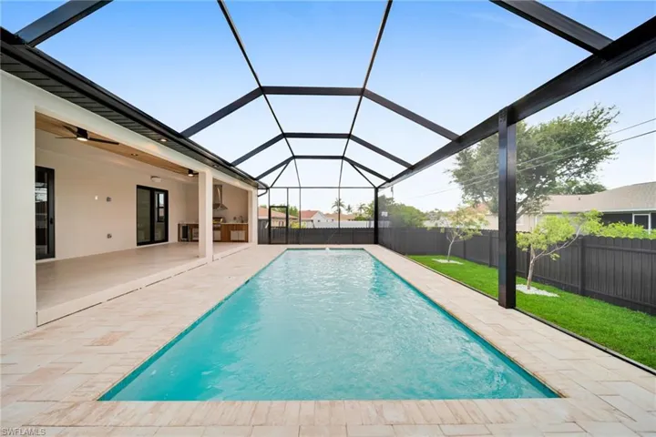 View of pool featuring a ceiling fan, a fenced backyard, a patio area, and glass enclosure