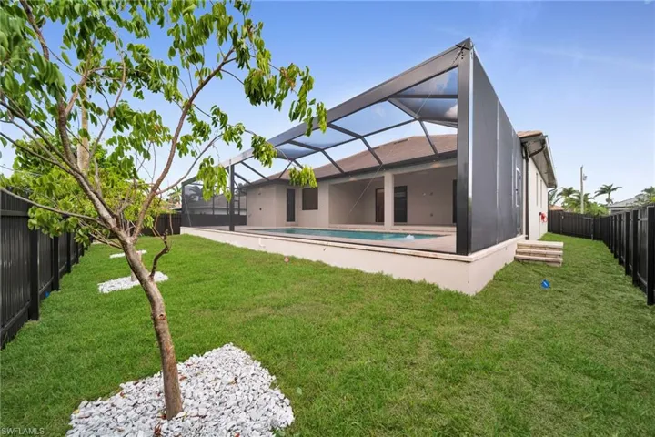 Back of property featuring a fenced backyard and a lanai