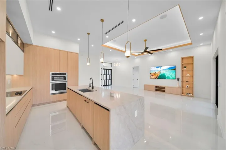 Kitchen with modern cabinets, stainless steel double oven, light brown cabinetry, and recessed lighting