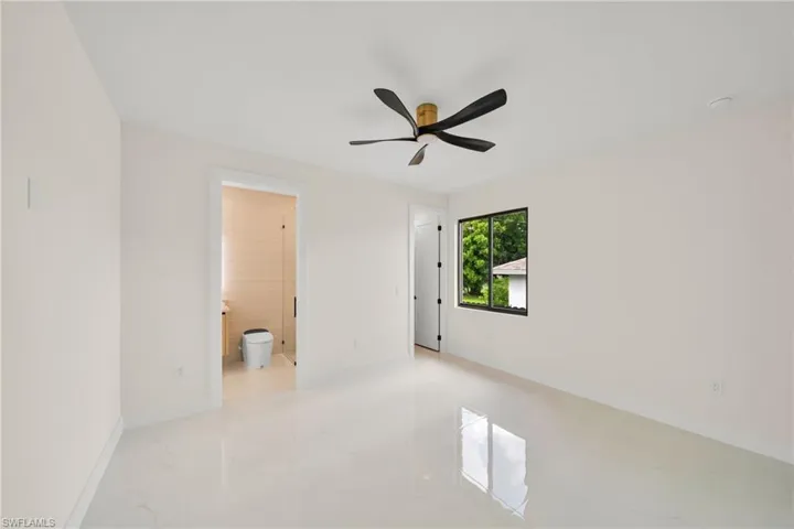 Spare room featuring light marble finish floors, ceiling fan, and a smoke detector