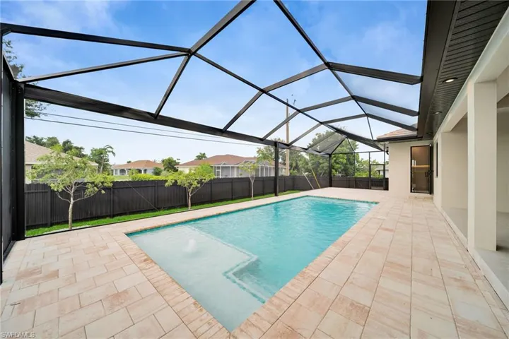 View of pool with a patio area, a fenced backyard, and glass enclosure