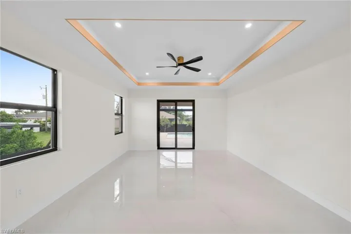 Spare room featuring marble tiled floors, a raised ceiling, recessed lighting, and ceiling fan