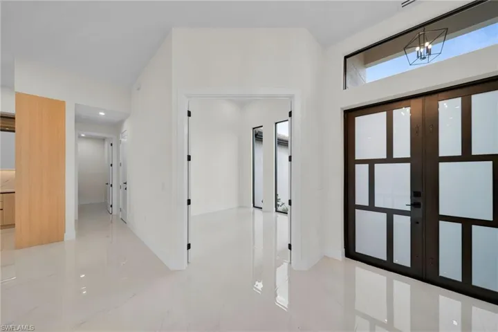 Entrance foyer with french doors, a chandelier, and light marble finish flooring